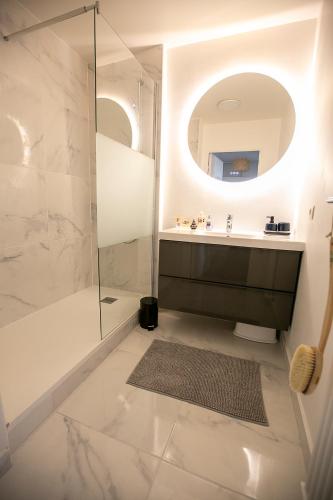 une salle de bain avec une douche, un lavabo et un miroir dans l'établissement Jerickais appartement à la Défense, à Courbevoie