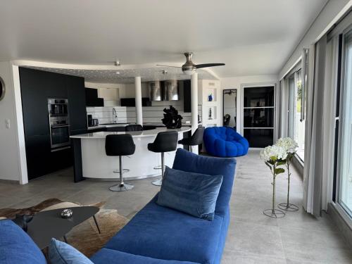 un salon avec un canapé bleu et une cuisine dans l'établissement 100m2 de paradis en total vue Mer, à Saint-Georges-de-Didonne