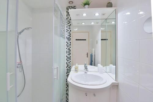 une salle de bain blanche avec un lavabo et un miroir dans l'établissement LES BEAUX JOURS Super nice flat for 3 with AC, balcony & view, à Antibes