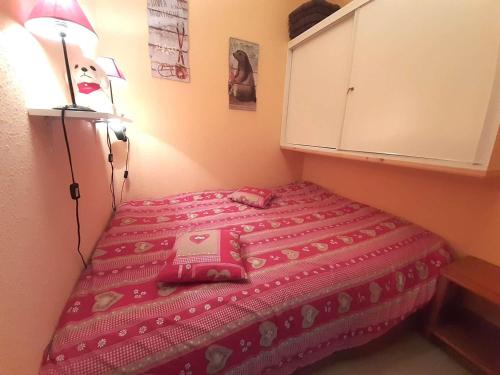 - une petite chambre avec un lit et une couverture rose dans l'établissement Studio cosy 4 couchages à Saint-Lary-Soulan avec kitchenette équipée - FR-1-457-334, à Saint-Lary-Soulan