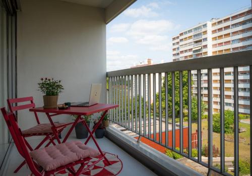 un balcon avec une table rouge et un ordinateur portable dessus dans l'établissement Le coquet à 20min de Paris et de l'aéroport d'Orly, à Juvisy-sur-Orge
