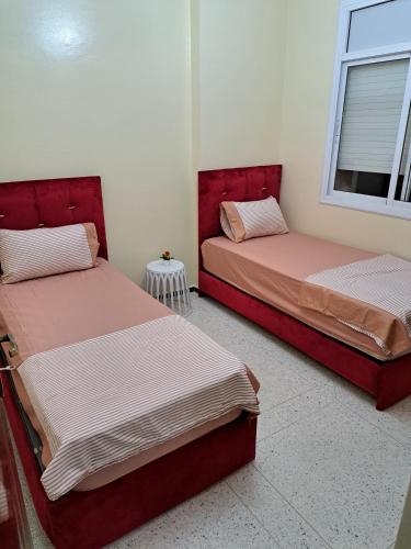 two beds in a room with red headboards at Appartement Atlas City Center in Fès