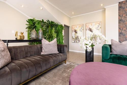 a living room with a brown couch and green chairs at MINT Hotel 84 on Katherine in Johannesburg
