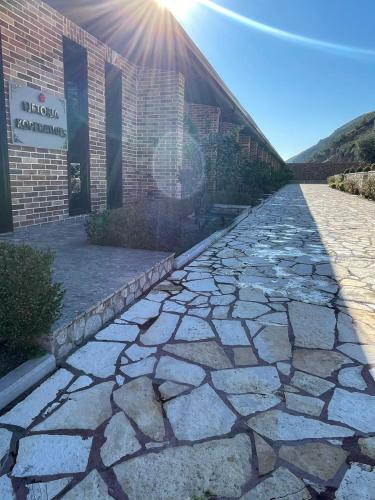 a stone walkway in front of a building with the sunlight at Rozafa Fish City Hotel in Labinot i Poshtëm