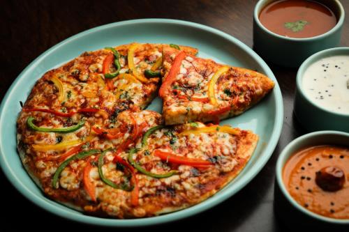 a plate of pizza on a table with two slices at Avhyay Resort in Māndvi