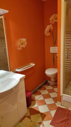 La salle de bains orange est pourvue de toilettes et d'un lavabo. dans l'établissement Chambre d'Hôtes La Closerie, à Tourneville
