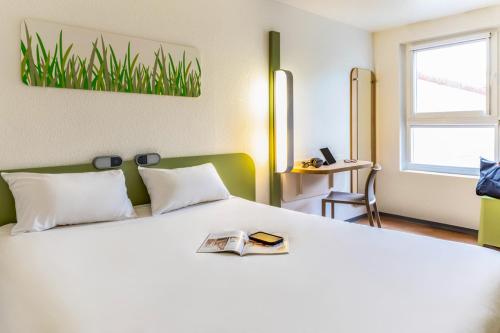 a bedroom with a white bed with a book on it at ibis budget Compiègne Centre-Ville in Compiègne