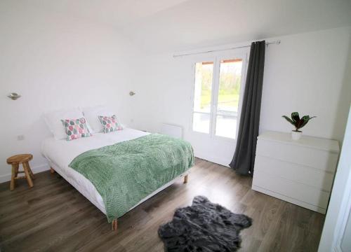- une chambre avec un lit doté d'une couverture verte et d'une fenêtre dans l'établissement Maison au bord du canal, à Moret-sur-Loing