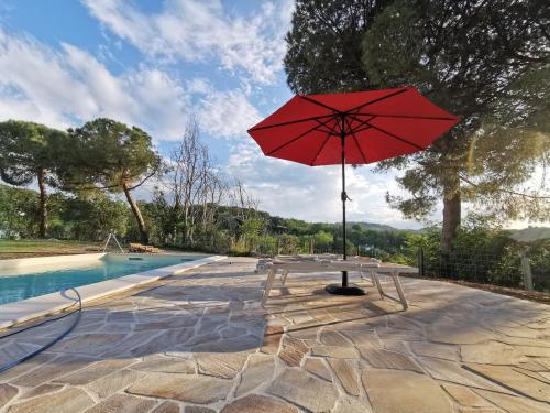 a red umbrella sitting next to a pool at Codirosso - Rustico in collina vicino al mare in Trebbiantico