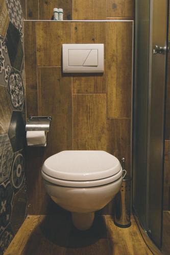 a toilet in a bathroom with wooden walls at 4 Rooms 1940 in Gjirokastër