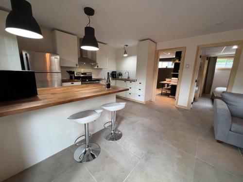 a kitchen and living room with two stools and a counter at La Renardière des Monts in Les Éboulements