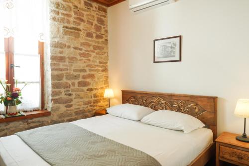 a bedroom with a bed and a brick wall at 4 Rooms 1940 in Gjirokastër