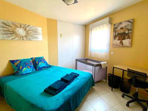 a bedroom with a blue bed and a desk at Le Familial, Piscine Plage et Garage in Villeneuve-Loubet