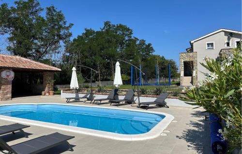 a swimming pool with chairs and umbrellas in a yard at 4 Bedroom Stunning Home In Lopar in Lopar