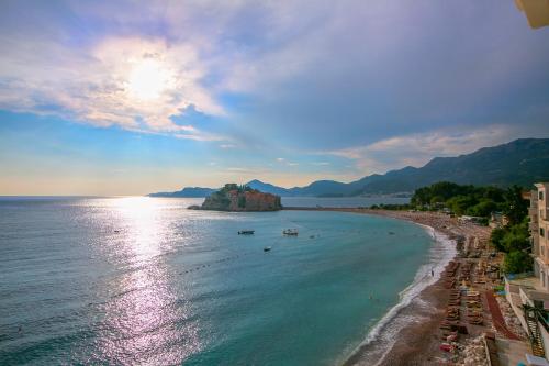 a view of a beach with the sun shining on the water at Montesan Luxury Apartment Beach Front in Sveti Stefan