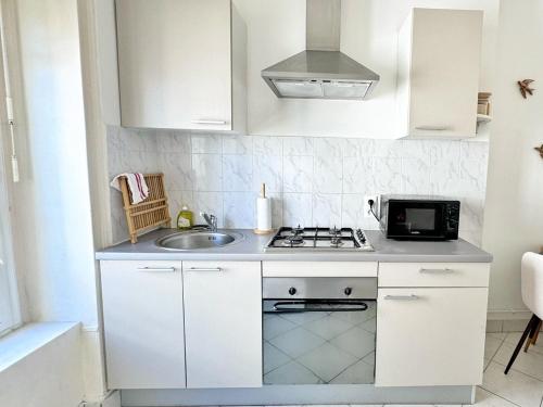 a white kitchen with a sink and a microwave at Suite Cinnabar - Check in h24 - Wifi in Oullins