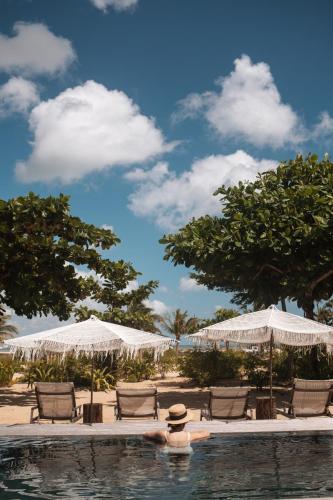 a pool with chairs and umbrellas on a beach at Villa Praia - La Villa Group in Jericoacoara
