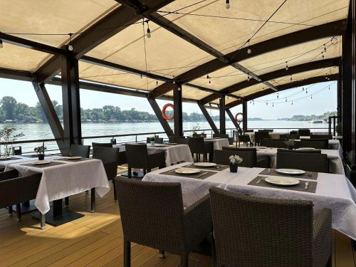 a restaurant with tables and chairs with a view of the water at KAME HOTEL BELGRADE,贝尔格莱德凯美酒店 in Ledine