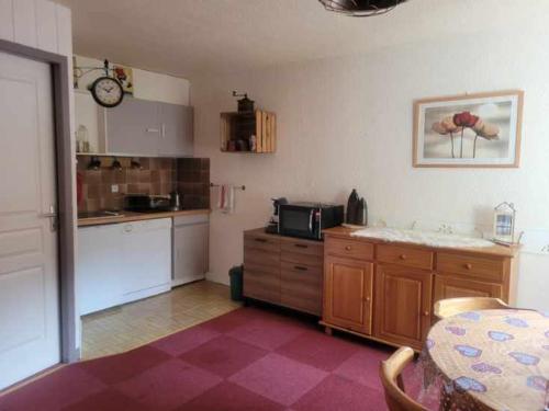 une cuisine avec un comptoir, une table et un four micro-ondes dans l'établissement Jolie studio pied des pistes, à Orcières