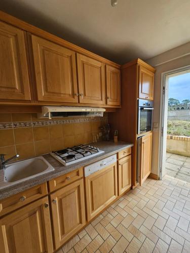 une cuisine avec des armoires en bois et un four à plaques de cuisson dans l'établissement La maison de vacances, à Foulognes