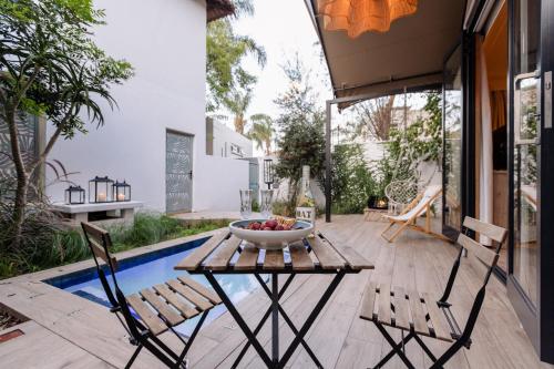 a table with a bowl of fruit on it next to a pool at MINT Hotel 84 on Katherine in Johannesburg