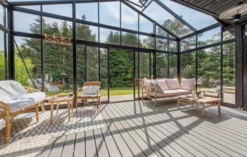 VejbyにあるLovely Home In Vejby With Kitchenのデッキにソファと椅子が置かれたガラス張りの温室