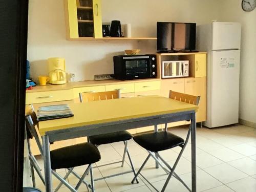 une cuisine avec une table, des chaises et un réfrigérateur dans l'établissement Appart de vacances, à Saint Pierre La Mer