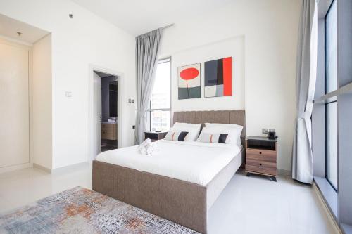 a white bedroom with a large bed and a window at Serenity Living - stunning 1BR, DAMAC Hills in Dubai