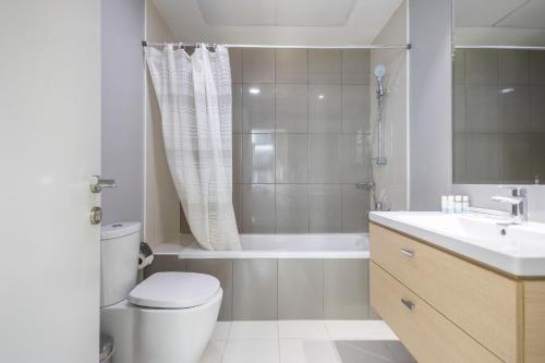 a bathroom with a toilet and a tub and a sink at Serenity Living - stunning 1BR, DAMAC Hills in Dubai