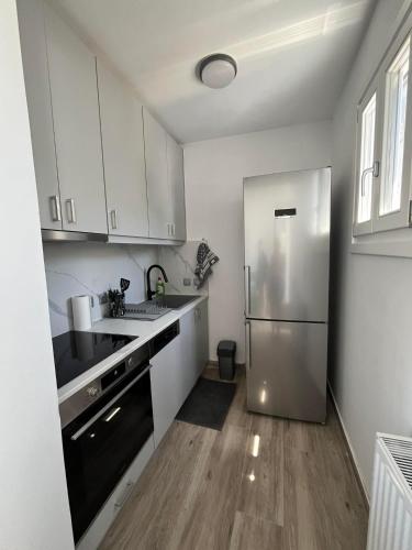 a kitchen with white cabinets and a stainless steel refrigerator at Anemi in Spetses
