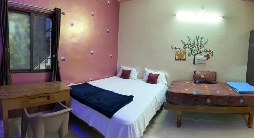 a bedroom with a bed and a table and a chair at ANU HOMESTAY in Hampi