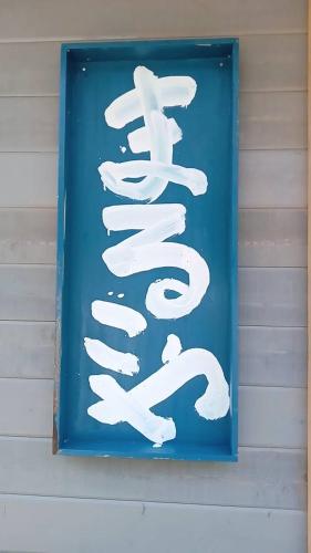 a blue sign with white writing on the side of a building at まるごや 船でしか行けない離島の一棟貸し宿 in Hinase
