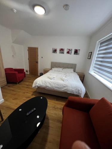 a bedroom with a bed and a red chair at The Barrington Hotel in New Barnet