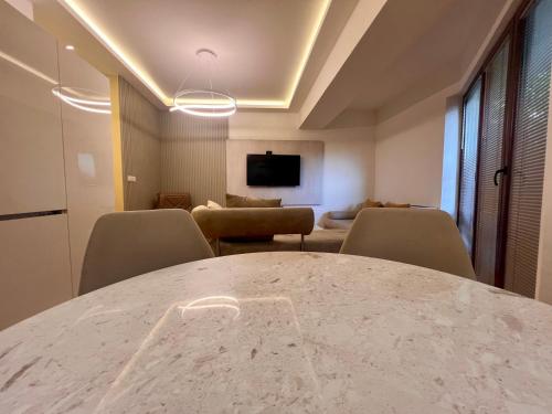 a room with a table and chairs and a tv at Gigi Apartment by eluxory in Skopje