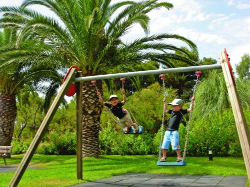 two young boys playing on a swing set at Hotel Club Le Plein Sud Vacances Bleues in Hyères