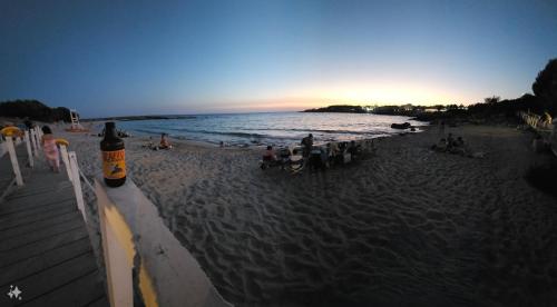 a beach with people sitting on the sand and the ocean at La nostra villetta in Pulsano