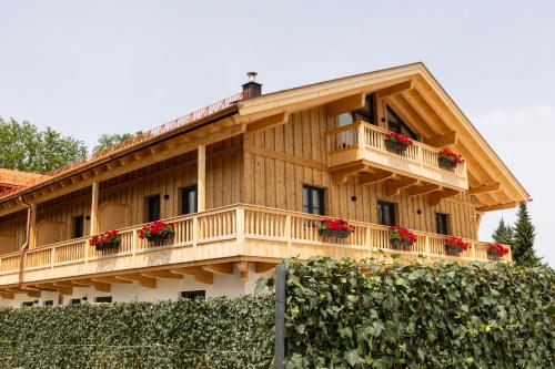 a wooden house with a balcony with red flowers at Hotel und Landgasthof Zachschuster in Gaißach