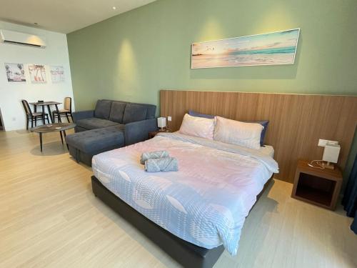 een slaapkamer met een bed, een bank en een stoel bij Freedom Flamingos-RoxyBeachApt in Sematan