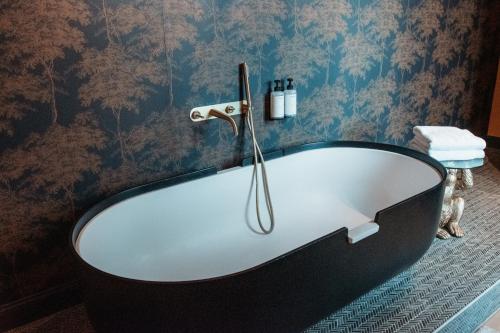 a bath tub in a bathroom with blue wallpaper at B&B Maison Mairie Hasselt in Hasselt