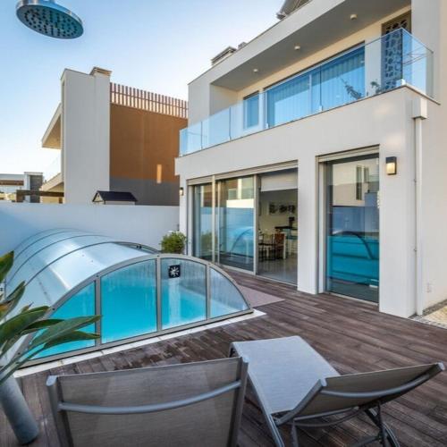 a house with a deck with chairs and a swimming pool at Silvercoast Villa Concha Baia with private heated pool and seaview rooftop lounge in Salir de Porto
