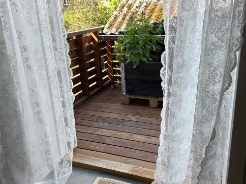 a porch with white curtains and a potted plant at SleepOrup in Faxe