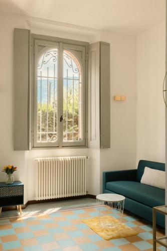 a living room with a blue couch and a window at Villa Locana con Jacuzzi e vista lago in Laglio