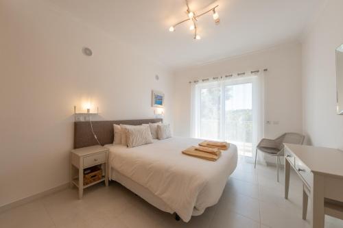 a white bedroom with a bed and a window at Porto de Mos 69 by Destination Algarve in Porto de Mós