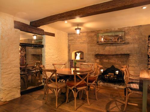 a dining room with a stone fireplace and a table and chairs at The Bear Of Rodborough Hotel in Stroud