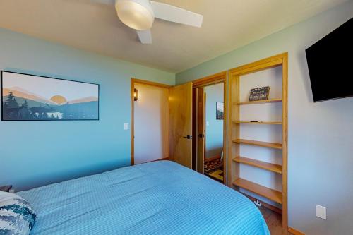 a bedroom with a blue bed and a flat screen tv at Bottle Bay View Lodge in Sagle