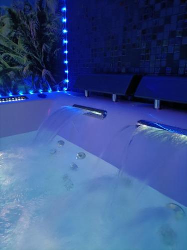 - une baignoire avec des lumières bleues dans la chambre dans l'établissement L'instant romance Le lagon, à Castelnaudary