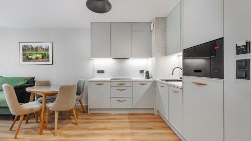 a kitchen with white cabinets and a table with chairs at Apartamenty Helski Brzeg in Hel