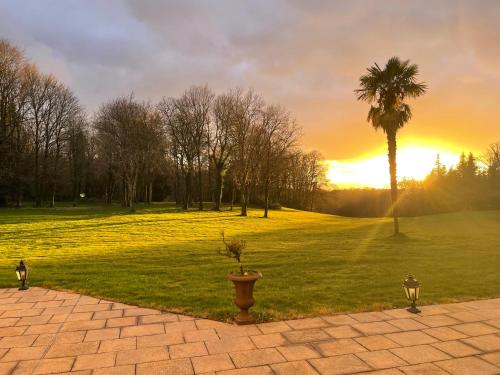 a sunset in a park with a palm tree at Château de Lannouan in Landévant