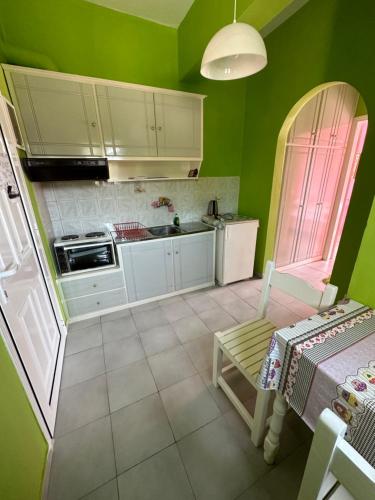 una pequeña cocina con paredes verdes y armarios blancos en Telis apartments, en Rodas