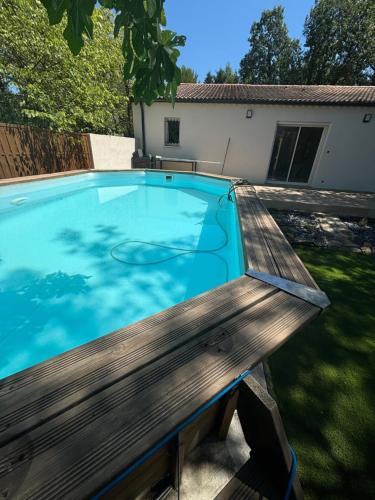 un banc en bois installé à côté d'une piscine dans l'établissement Maison au calme, piscine, terrain de pétanque, à Deaux